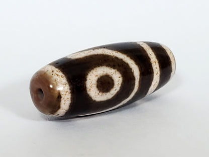Qing Dynasty two eye dzi — angled end, drill hole at warm brown-grey rounded right tip, spiral eye and stripes, At-0426-2EQ2