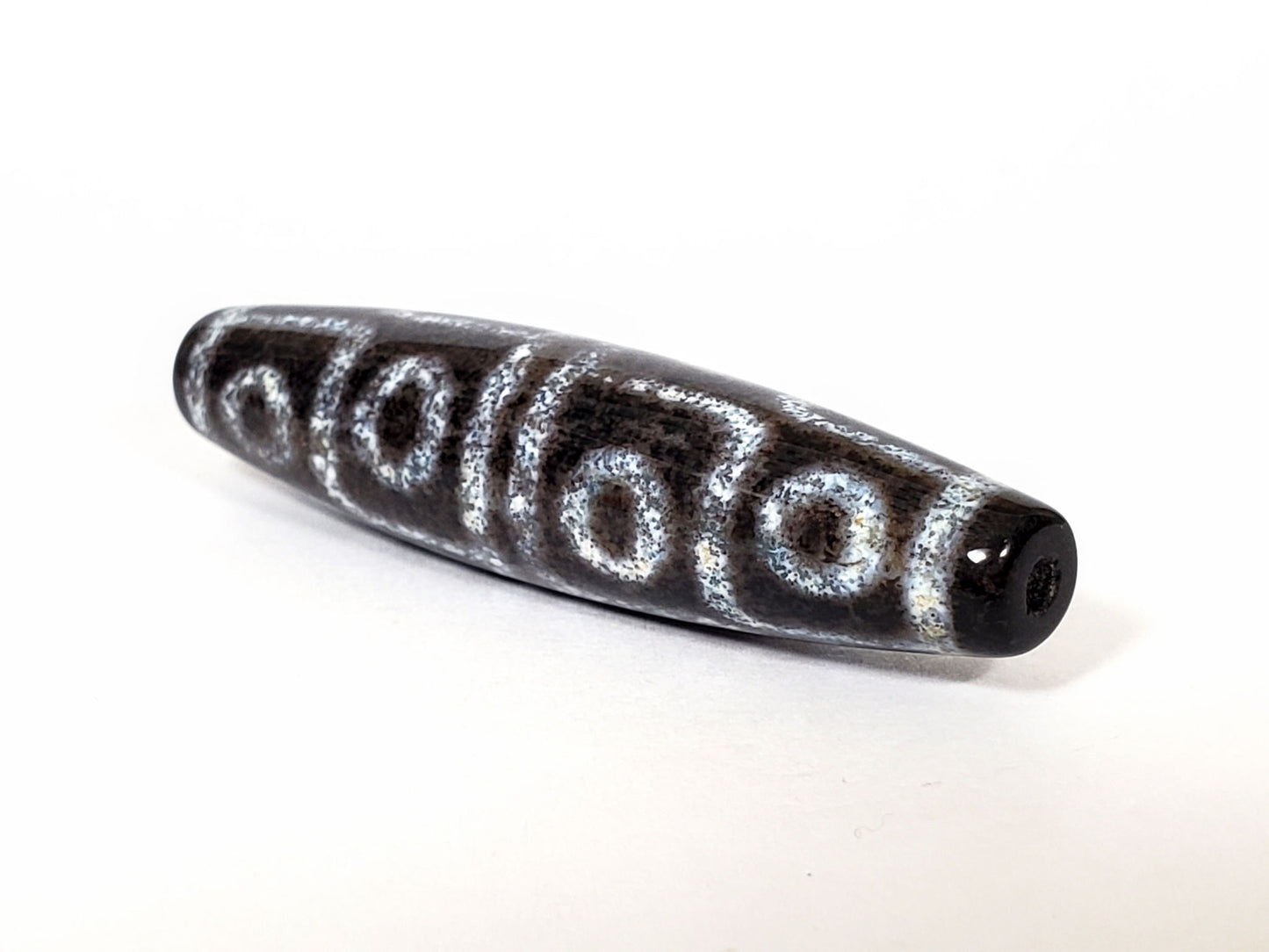 N-062126-12E-2 dzi bead, close side profile, visible surface speckling, unretouched