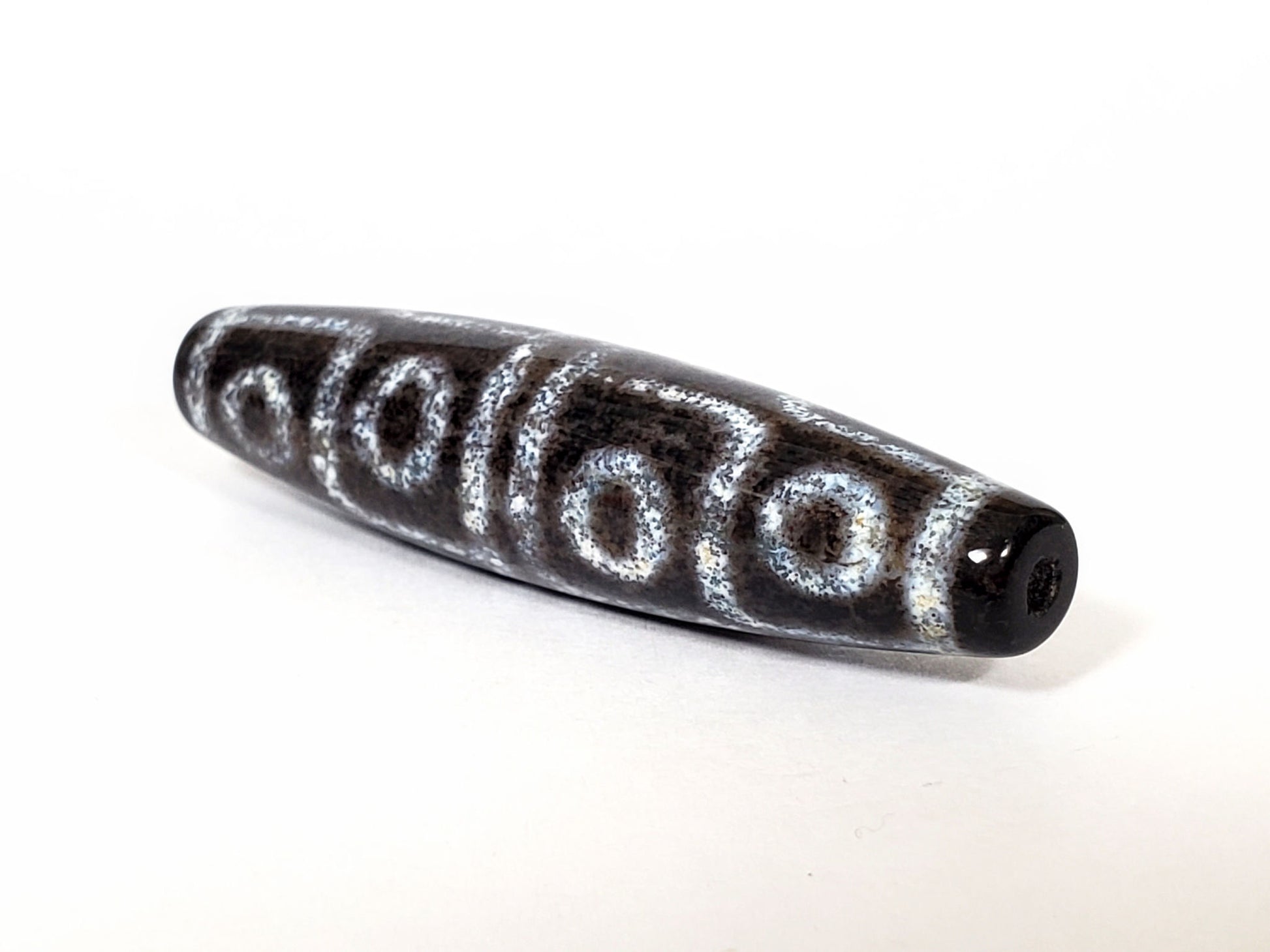 N-062126-12E-2 dzi bead, close side profile, visible surface speckling, unretouched