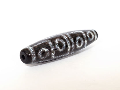 N-062126-12E-2 dzi bead, three-quarter angle showing drilled end, unretouched