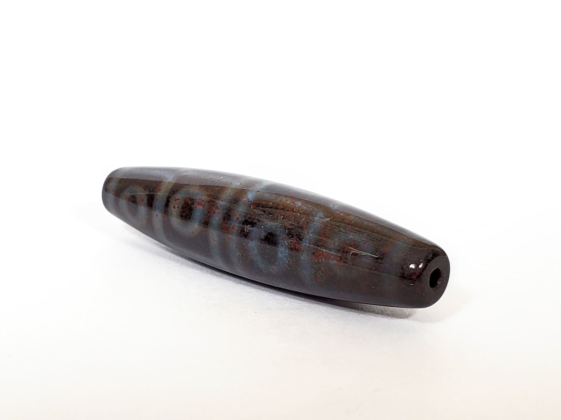 N-062126-12E-1 dzi bead, three-quarter angle showing drilled end, unretouched