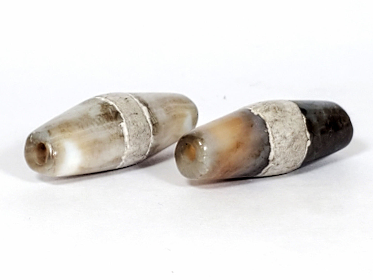 Ac-061526-1SPair, both beads opposite tips, Bead B warm honey-orange tip contrasting dark body, calcification zones, unretouched