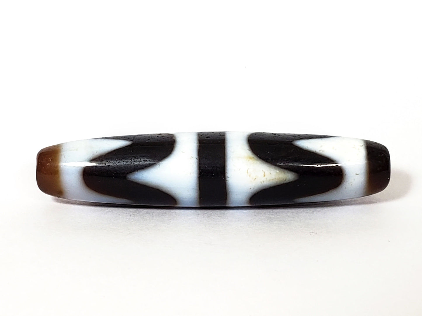 N-062226-DW3, double wave dzi, 57.8×12.6mm, very dark brown, cool white motif, honey-brown cap, face A, unretouched