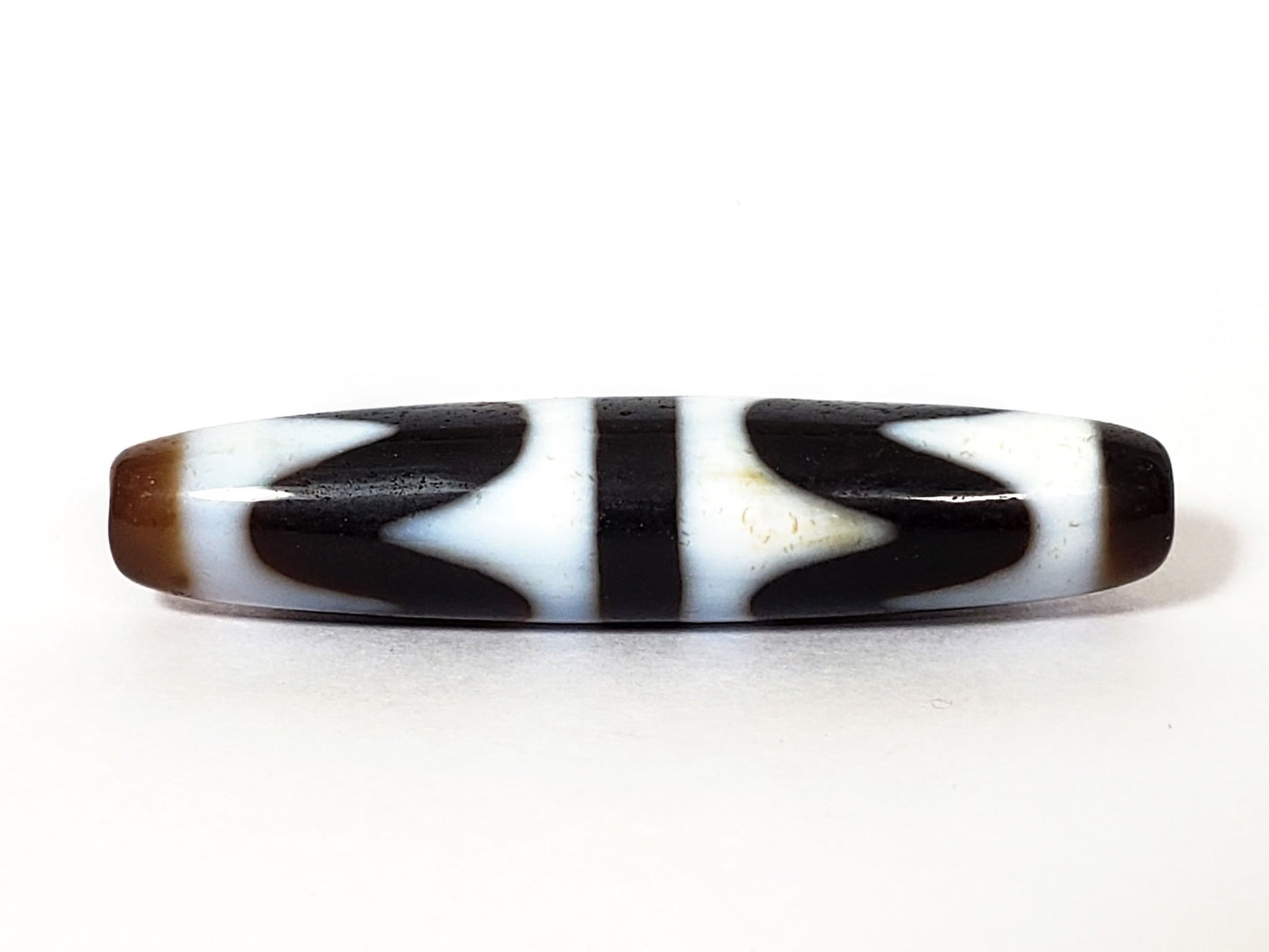 N-062226-DW3, double wave dzi, 57.8×12.6mm, very dark brown, cool white motif, honey-brown cap, face A, unretouched
