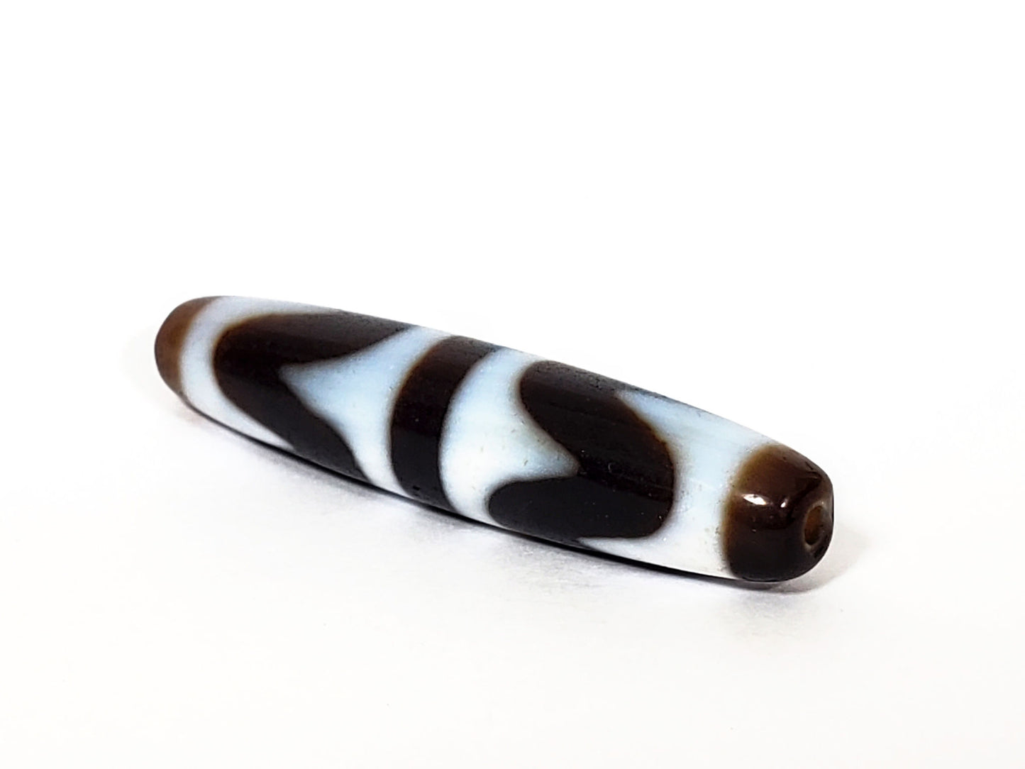 N-062226-DW3, angled view, honey-brown end cap with drill hole, very dark brown body, wave motif visible, unretouched