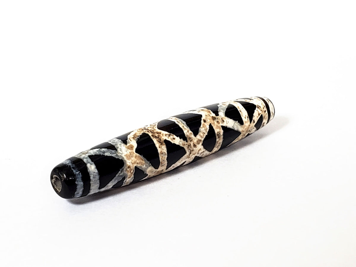 Ancient criss-cross motif carnelian dzi bead with natural agate patterning and weathered patina on white background