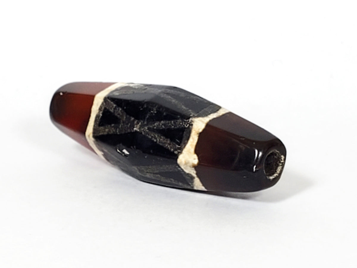 Ancient carnelian dzi bead hexagonal shape black criss-cross motif white border patterns drill hole visible aged patina