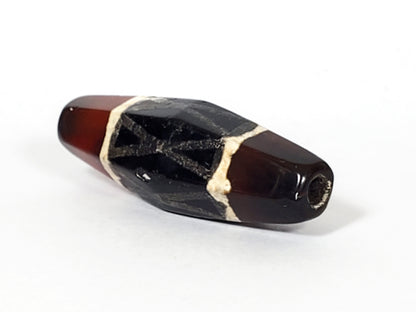 Ancient carnelian dzi bead hexagonal shape black criss-cross motif white border patterns drill hole visible aged patina