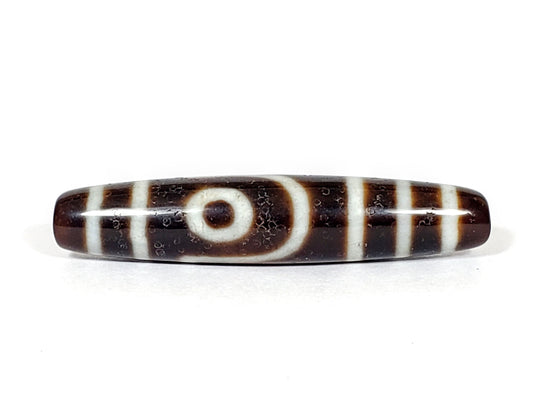 V-070226-2E vintage two eye dzi bead, front view, dark brown ground, cream eye motif, 56.6×11.9mm, unretouched.