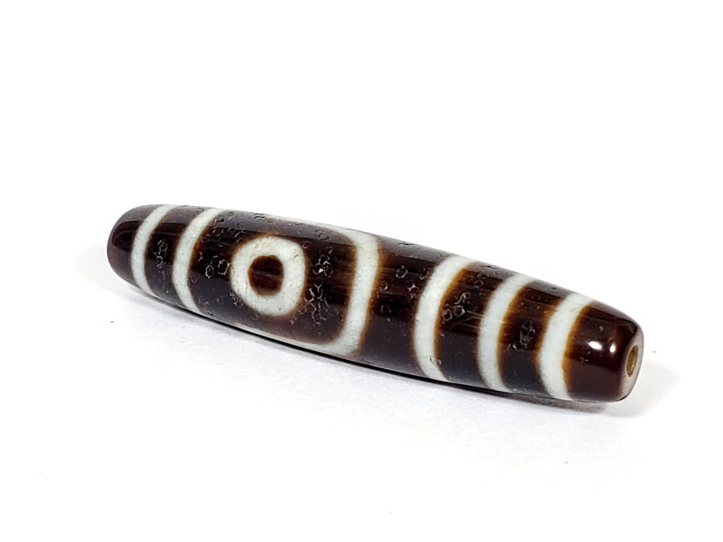 V-070226-2E dzi bead, angled view showing stepped-line face, dark brown, unretouched.