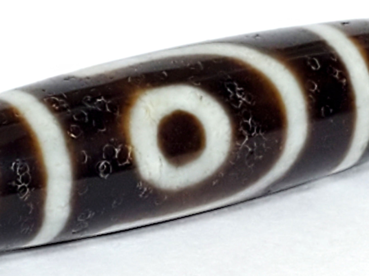 V-070226-2E dzi bead, macro view of eye motif showing natural surface pitting, unretouched.