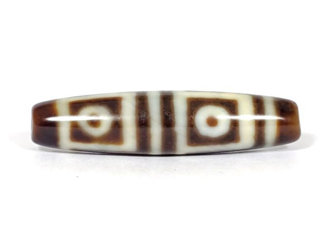 V-070226-4E vintage four eye dzi bead, front view, cream-white ground with dark brown motif, 49.4×11.9mm, unretouched.