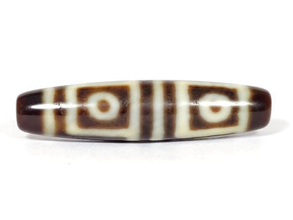 V-070226-4E dzi bead, angled view showing eye and step motif, dark brown on cream, unretouched.