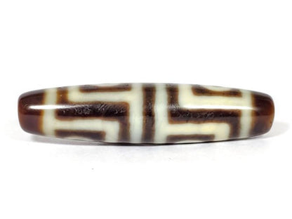 V-070226-4E dzi bead, reverse face, dark brown eye motif on cream-white ground, unretouched.