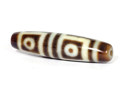 V-070226-4E dzi bead, diagonal view showing drill hole, dark brown motif, unretouched photo.