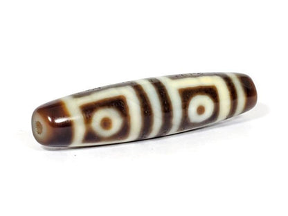 V-070226-4E dzi bead, full-length diagonal view, dark brown motif on cream ground, unretouched.