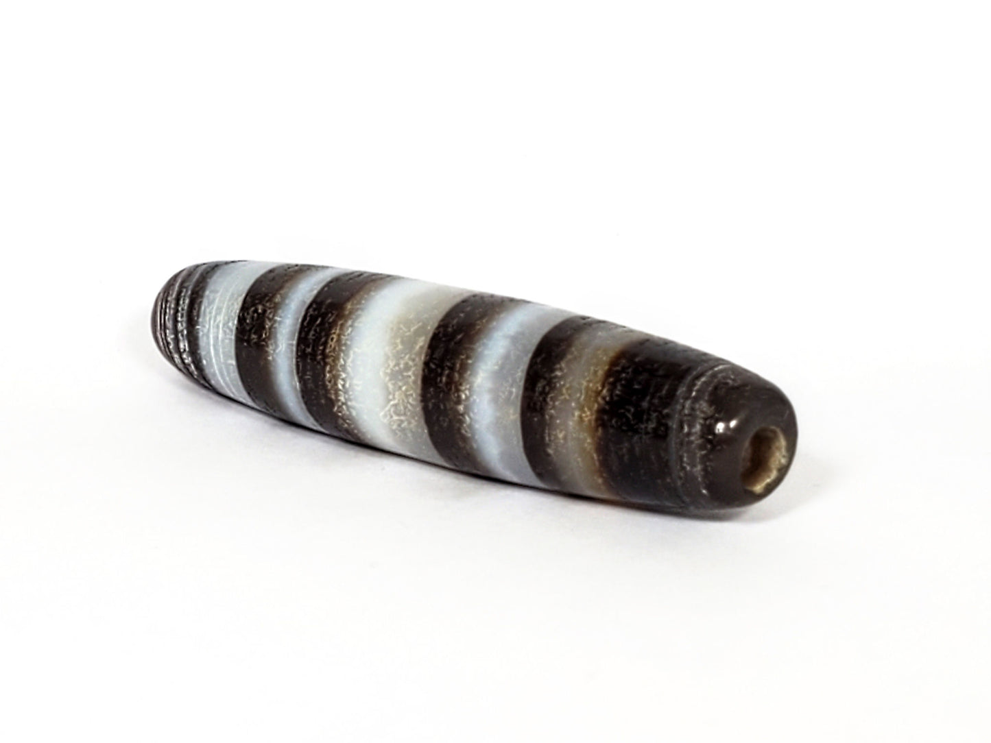 N-N-062126-CS1 natural agate dzi, three-quarter angle showing drill hole and ring-cluster end, unretouched