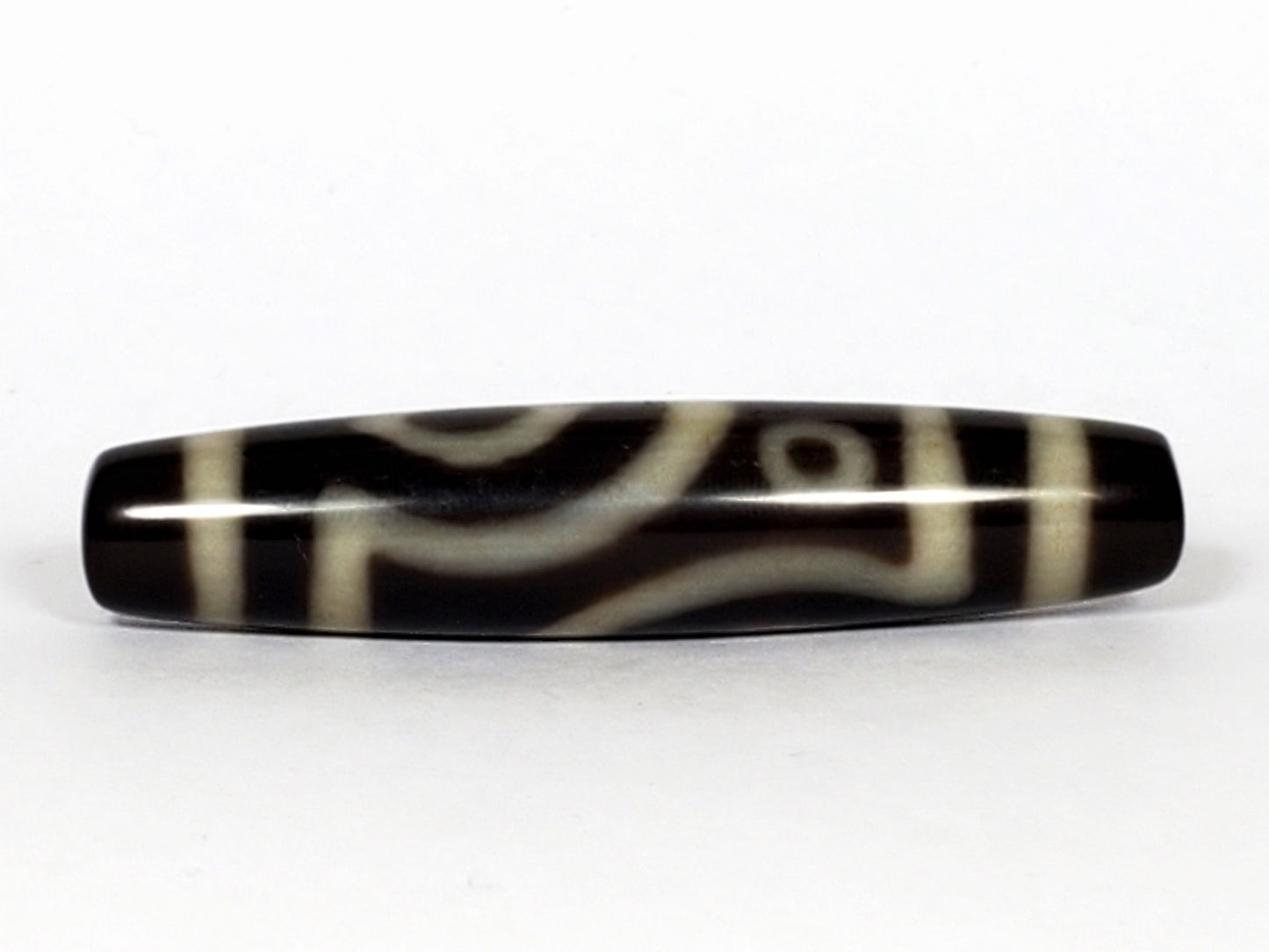 V-070226-4E2 dzi bead, curved connecting-line face, black ground, cream bands, unretouched photo.