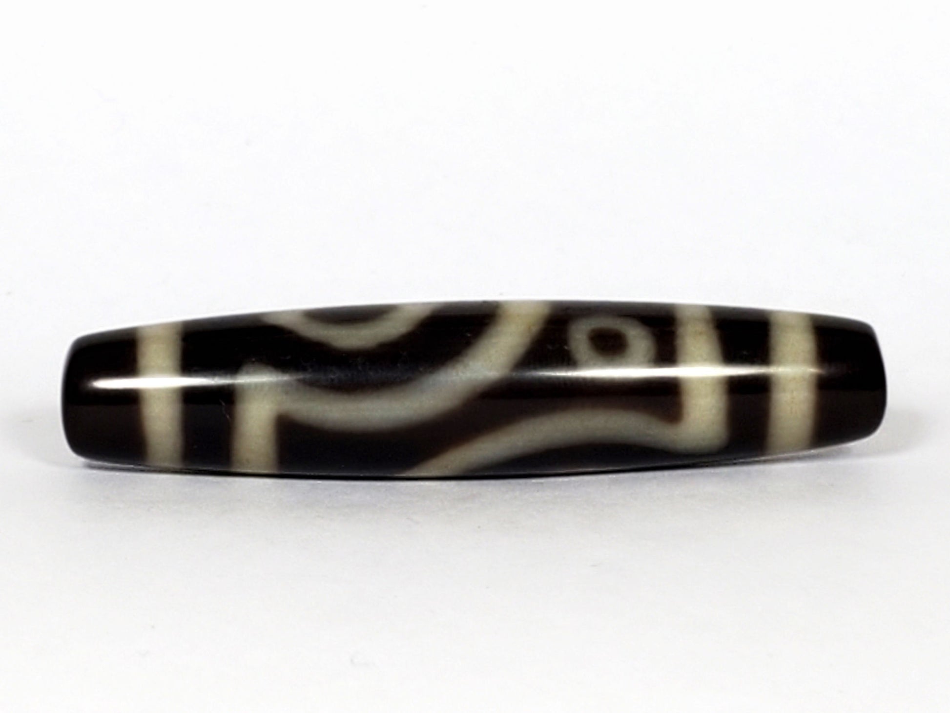 V-070226-4E2 dzi bead, curved connecting-line face, black ground, cream bands, unretouched photo.