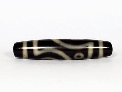 V-070226-4E2 dzi bead, angled view, curved cream lines on black ground, unretouched.