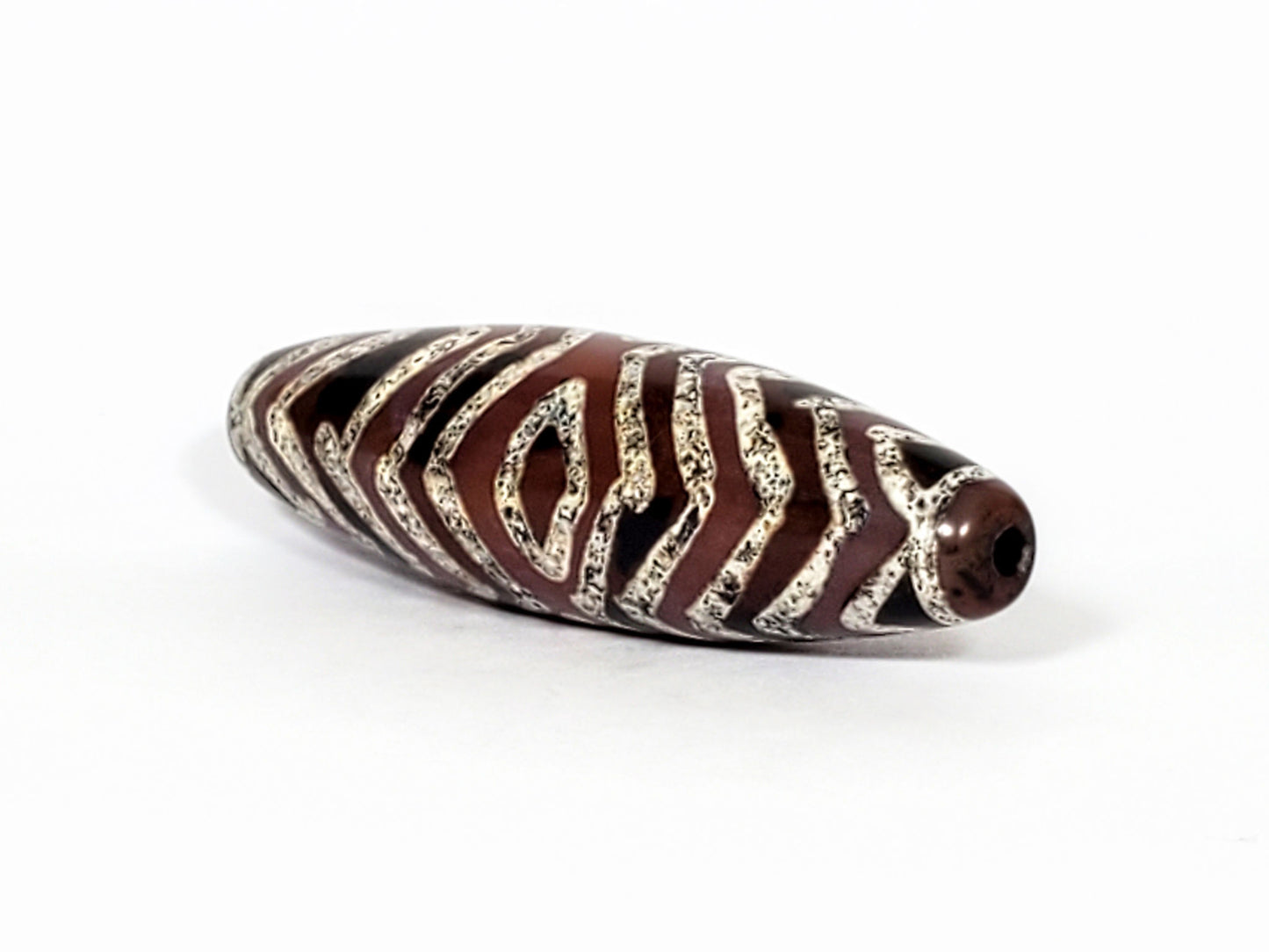 At-071322-3ETT antique carnelian dzi, angled right end view, drill hole, chevron tip detail, chocolate-brown, unretouched