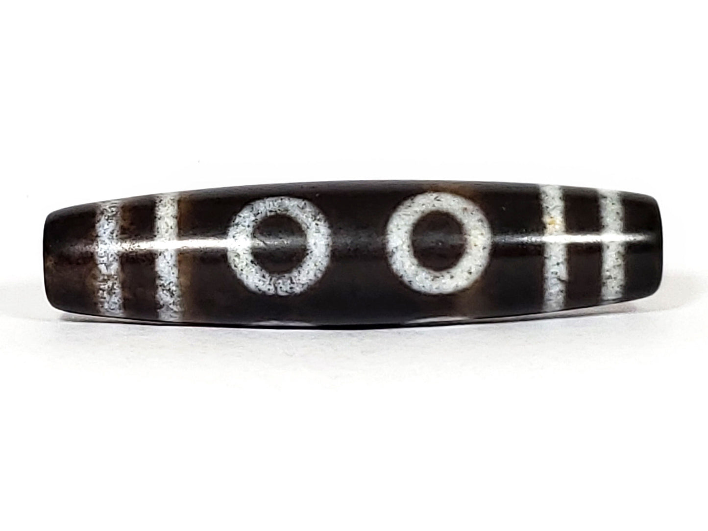 N-062226-6E, six eye agate dzi, 58.4×14.0mm, very dark brown, three closed ring eyes face A, off-white motif, unretouched