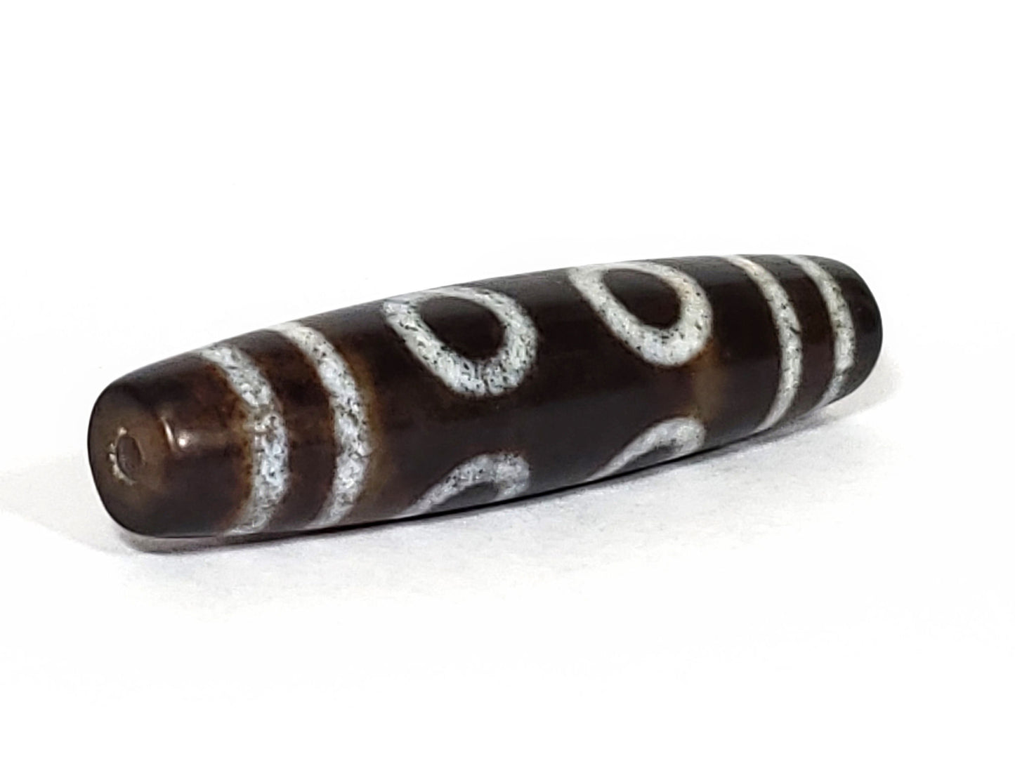 N-062226-6E, opposite angled view, bulbous end, drill hole centred, C-curve motif wrapping body, dark brown, unretouched