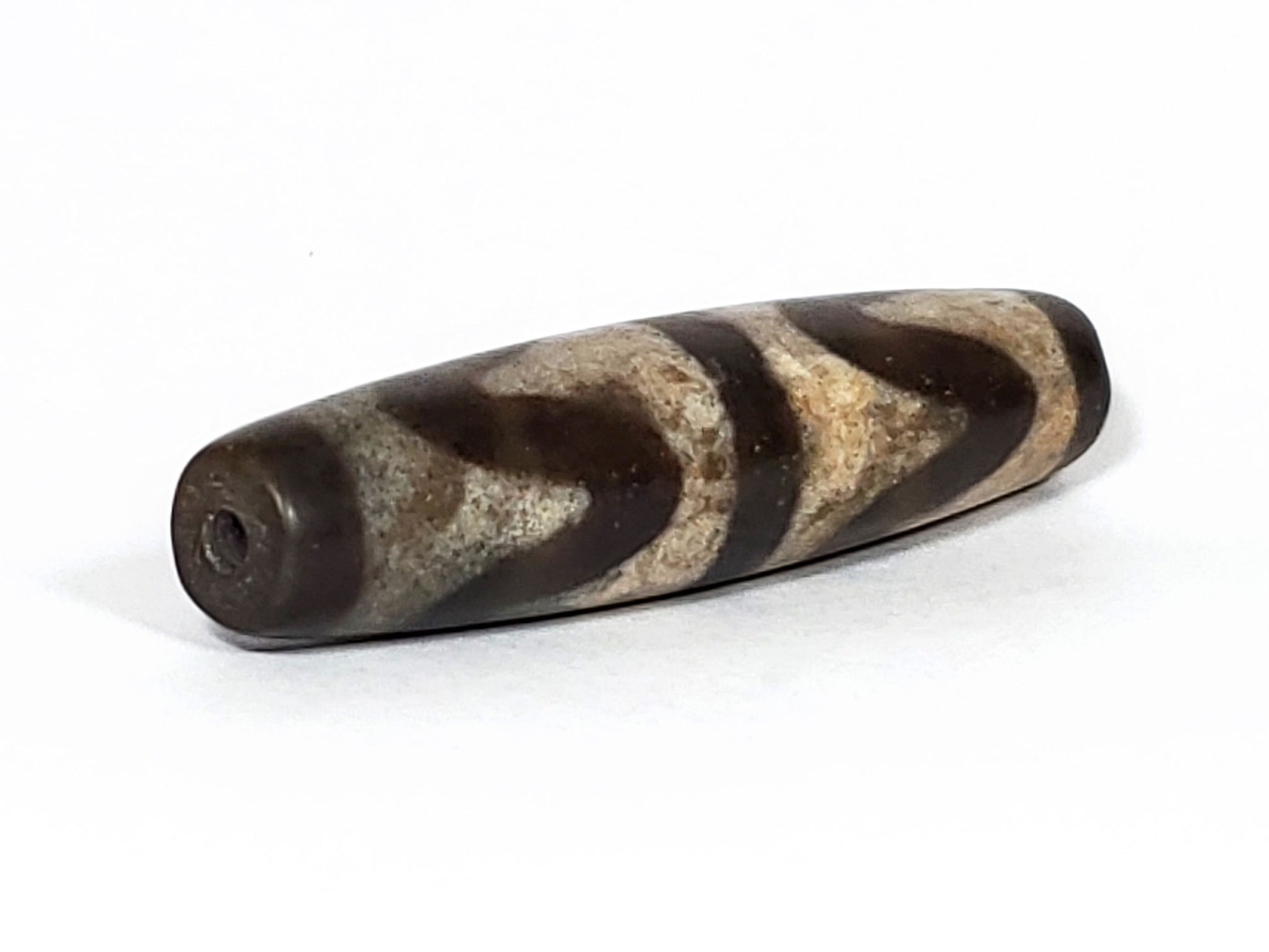 N-062226-DW2, opposite end angled view, drill hole centred, wave motif wrapping toward tapered tip, unretouched
