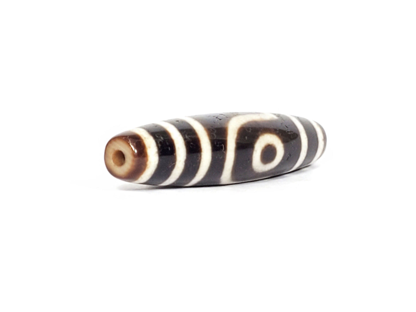 V-070426-2E3 dzi bead, diagonal view showing drill hole and eye motif, unretouched photo.