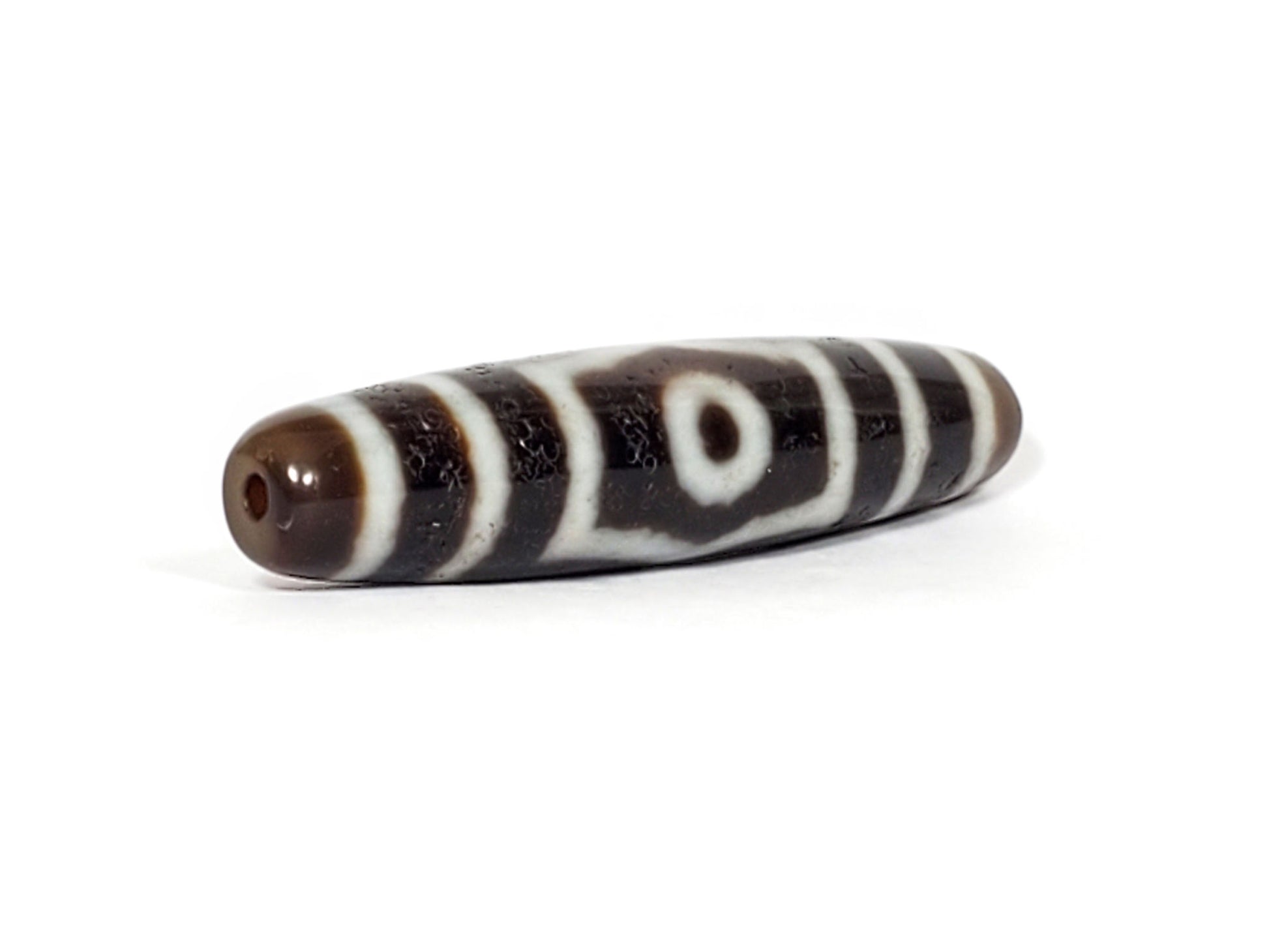 V-070226-ThE-001 dzi bead, diagonal view showing drill hole and stripe pattern, brown end, unretouched.