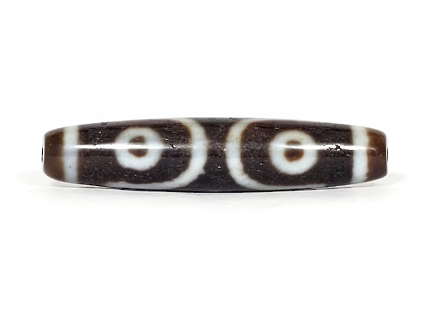 V-070226-ThE-001 dzi bead, reverse face showing two eyes with looping lines, unretouched photo.