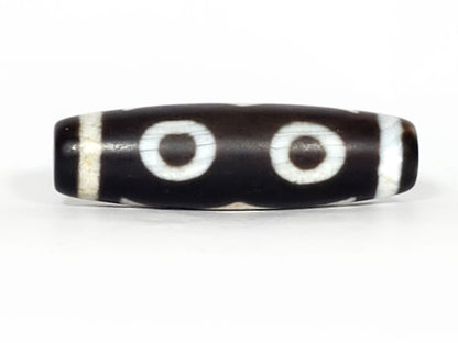 N-070226-3E dzi bead, reverse face, two eyes joined by wave motif on black ground, unretouched.