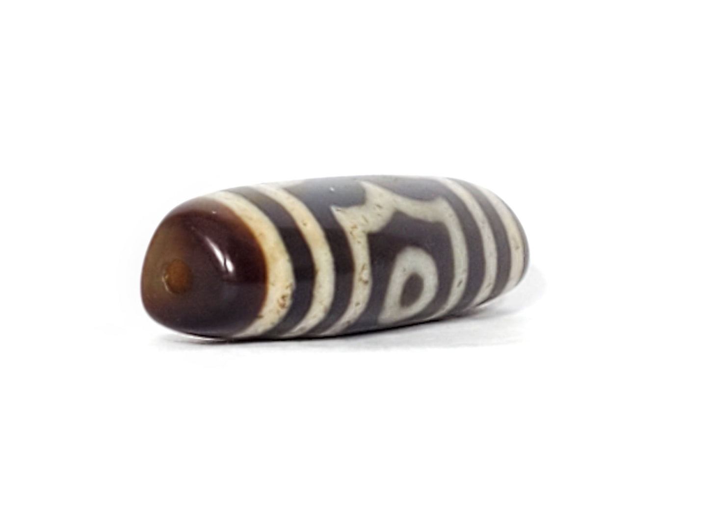 V-070226-3E dzi bead, diagonal view showing drill hole, dark brown end zone, unretouched photo.