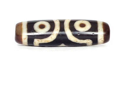 V-070226-3E dzi bead, two-eye spiral face, black ground with cream motif, unretouched photo.