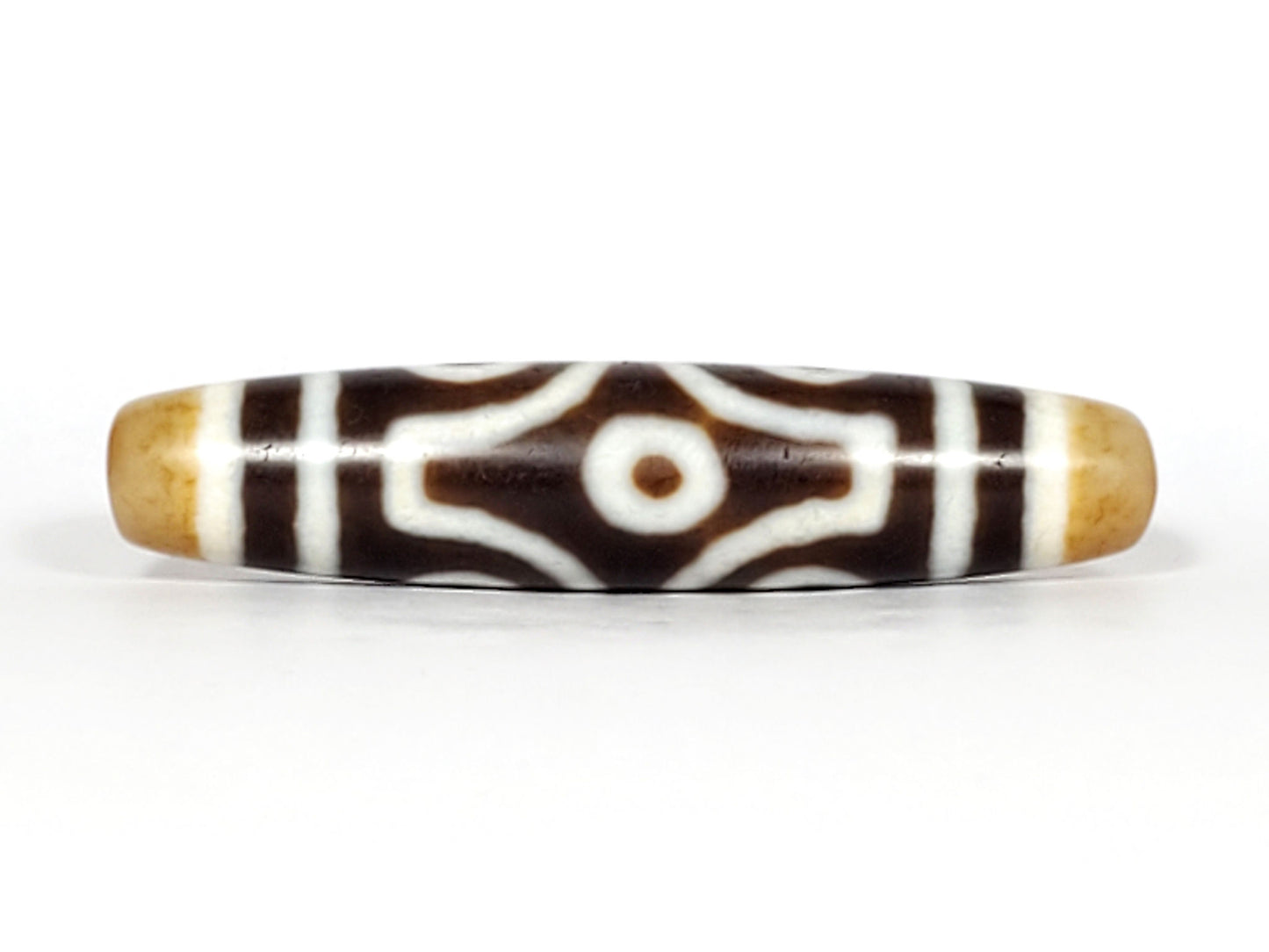 Face B of antique six eye dzi At-053026-6E, single concentric-ring eye centred in diamond star frame, cross-grid stripes, deep brown agate, honey-gold end caps, unretouched