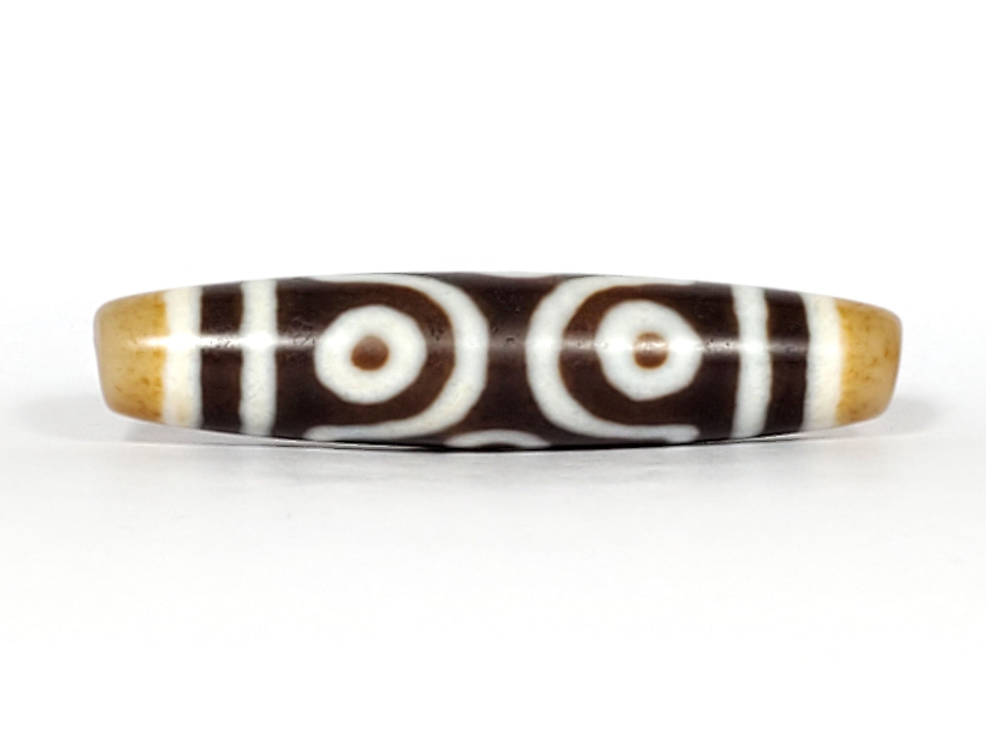Face C of antique six eye dzi At-053026-6E, two fully closed concentric-ring eyes with scroll connector, deep brown agate, honey-gold end caps, 54.9mm, unretouched photography