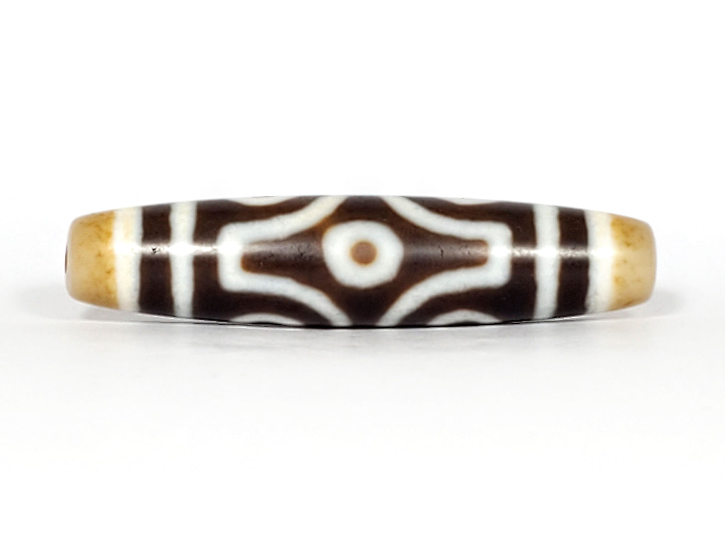 Face D, diamond frame single eye): Face D of antique six eye dzi At-053026-6E, single eye within diamond compass-rose frame on deep brown agate, honey-gold end caps, 54.9mm × 12.3mm, unretouched