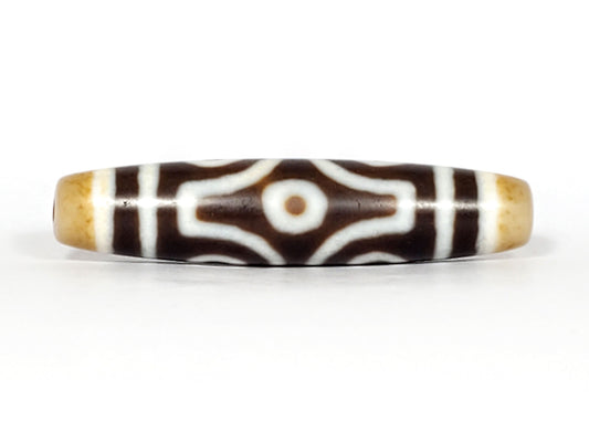 Face D, diamond frame single eye): Face D of antique six eye dzi At-053026-6E, single eye within diamond compass-rose frame on deep brown agate, honey-gold end caps, 54.9mm × 12.3mm, unretouched
