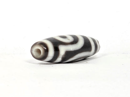 End cap view of antique two eye dzi bead At-010726-2E3, dark brown agate tip, drill hole centred, torpedo body tapering, near-black agate, 38.6mm