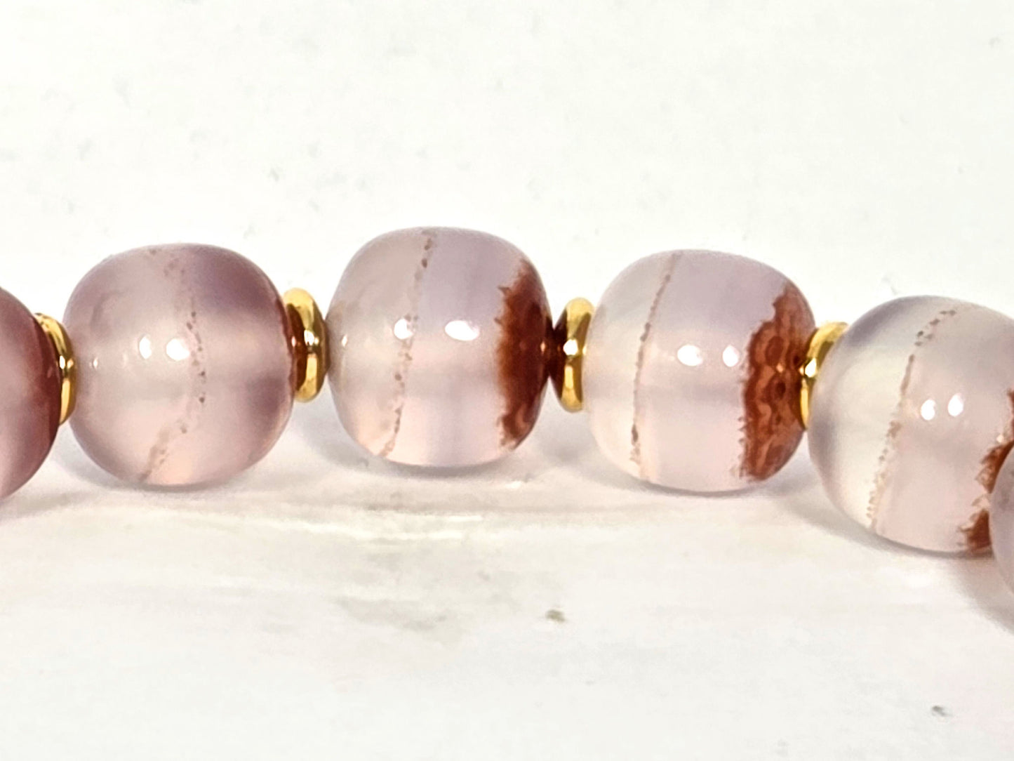 N-020726-CB3 row detail, russet-brown cinnabar sweep zones and fine lines in pale chalcedony, gold spacers, unretouched