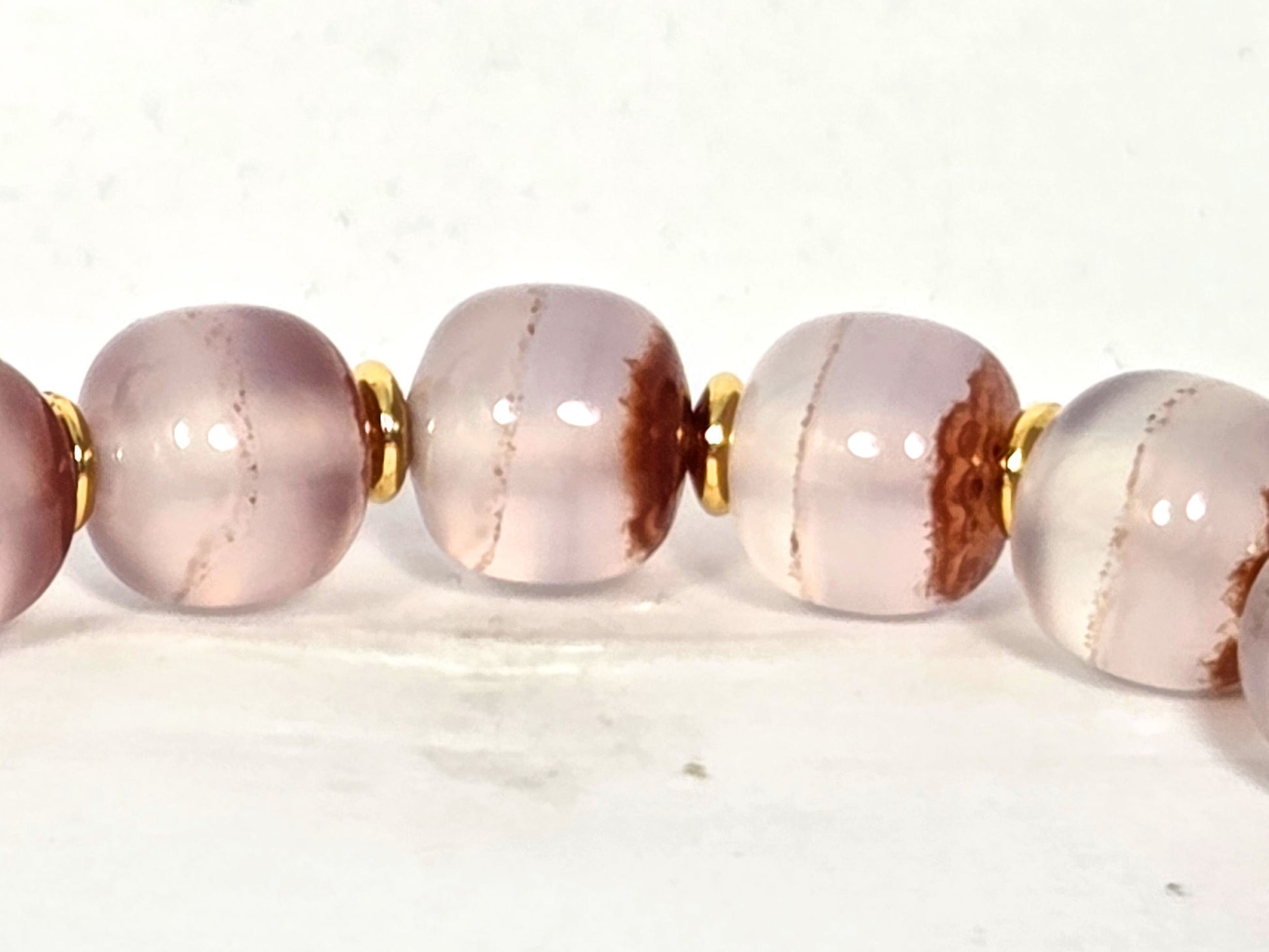 N-020726-CB3 row detail, russet-brown cinnabar sweep zones and fine lines in pale chalcedony, gold spacers, unretouched