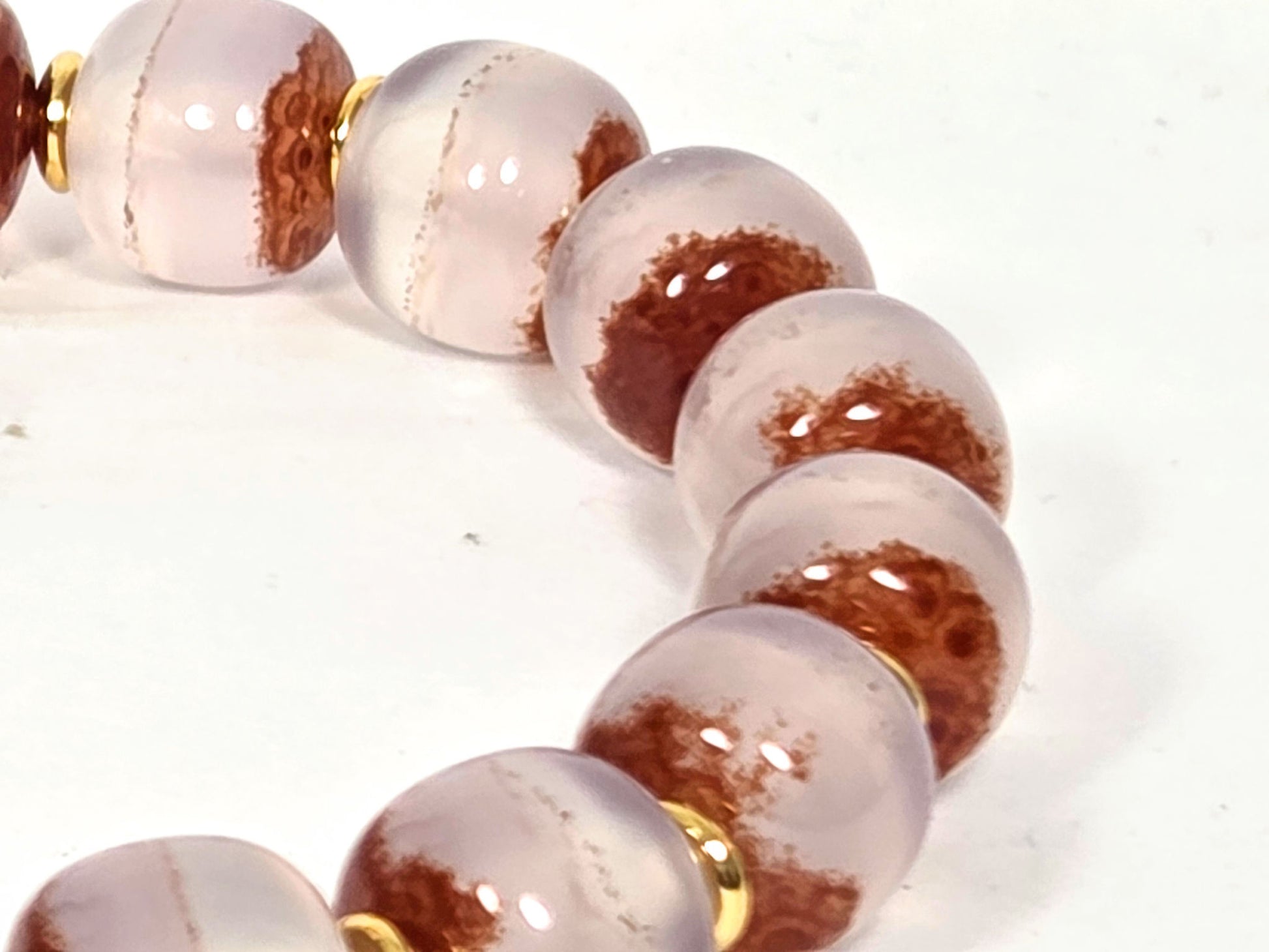 N-020726-CB3 macro, consecutive beads with bold rust-orange cinnabar mass zones, pale chalcedony ground, unretouched