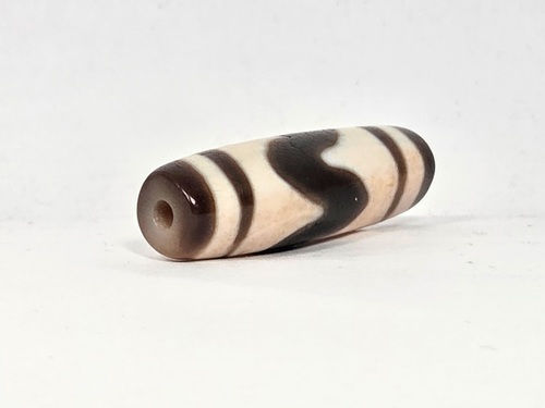 V-030326-TTBS vintage tiger tooth dzi, second angled end shot, cream end cap, dark dark brown motif visible, unretouched.