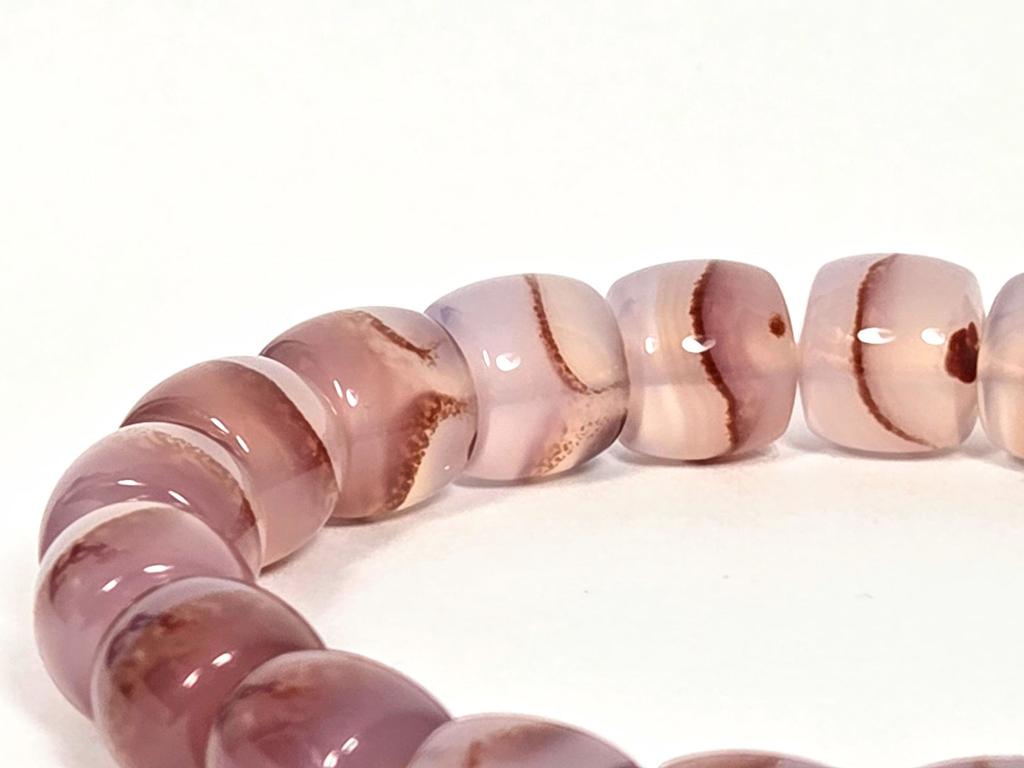 N-030526-CB bead row, dusty mauve-rose chalcedony, rust-brown sweep banding, cinnabar dot inclusions, unretouched