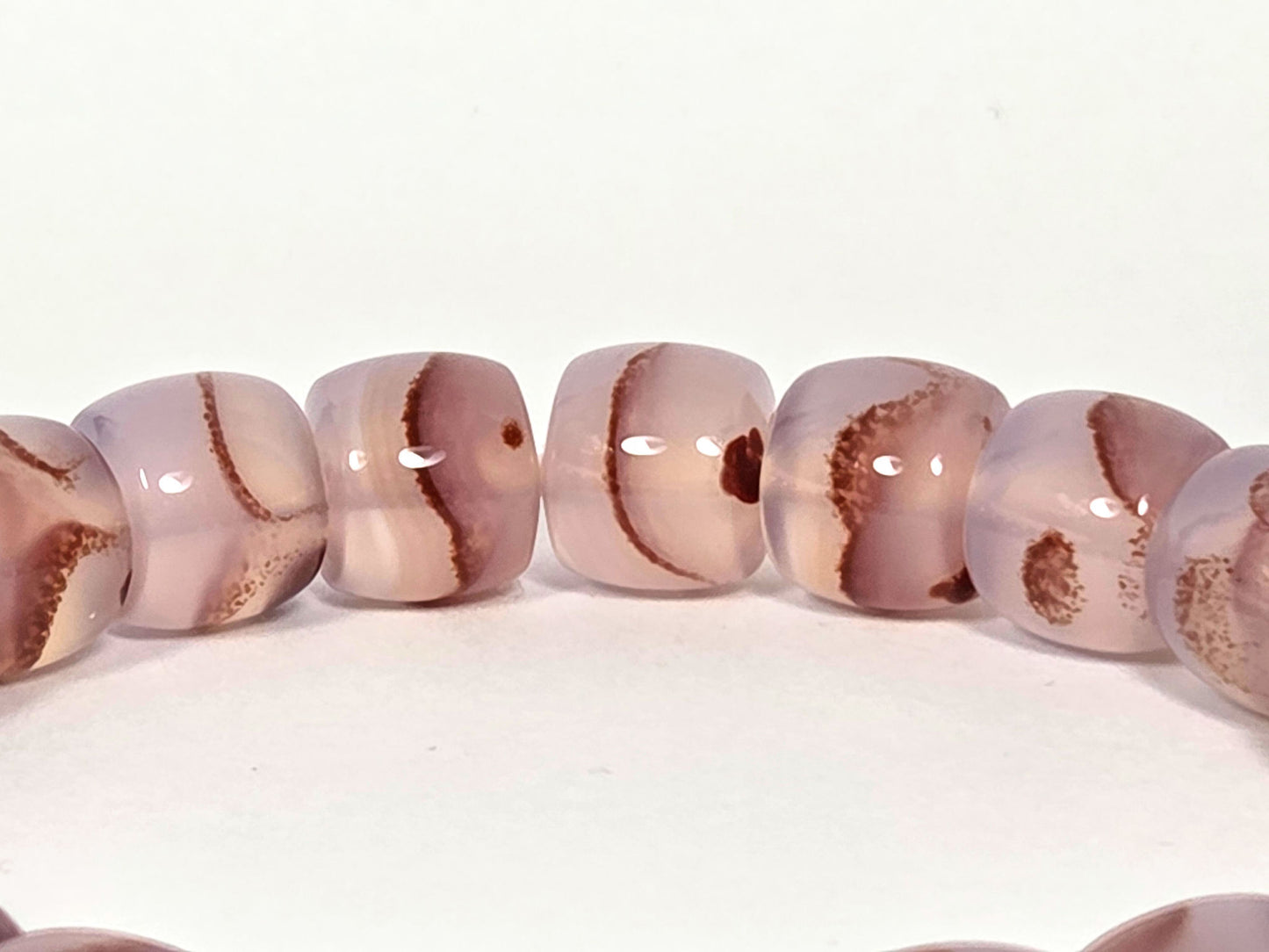 N-030526-CB macro, dark rust-brown cinnabar inclusion masses in mauve-rose chalcedony beads, unretouched