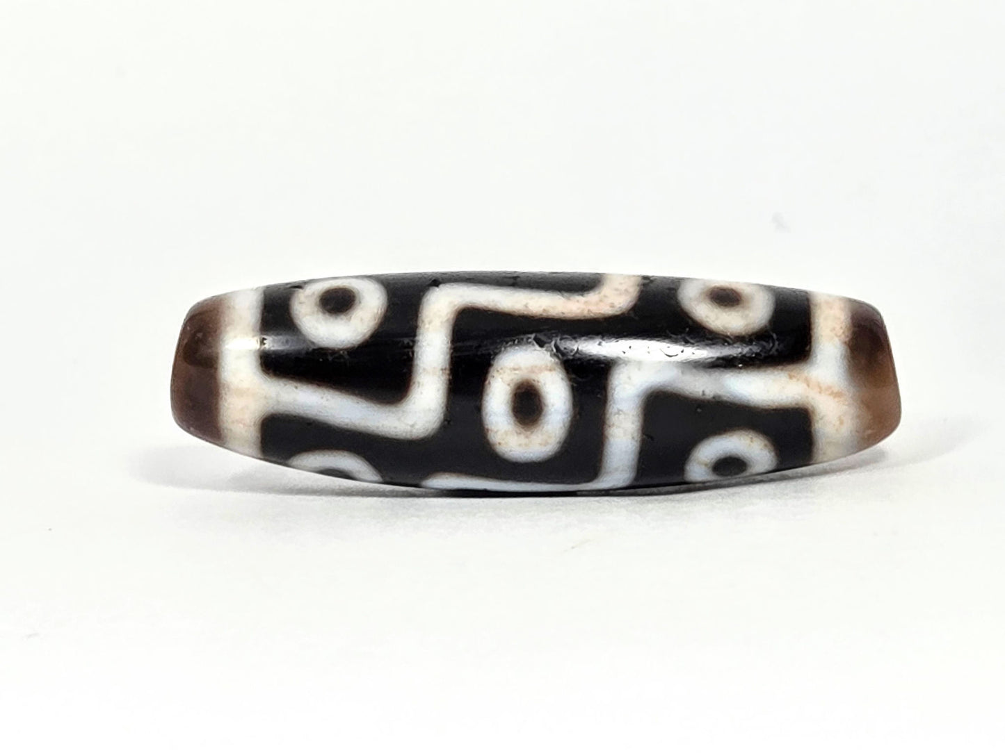 At-070626-9EBS antique nine eye dzi face B, black ground, warm brown end caps, bold cream stepped eye motif rotated, unretouched
