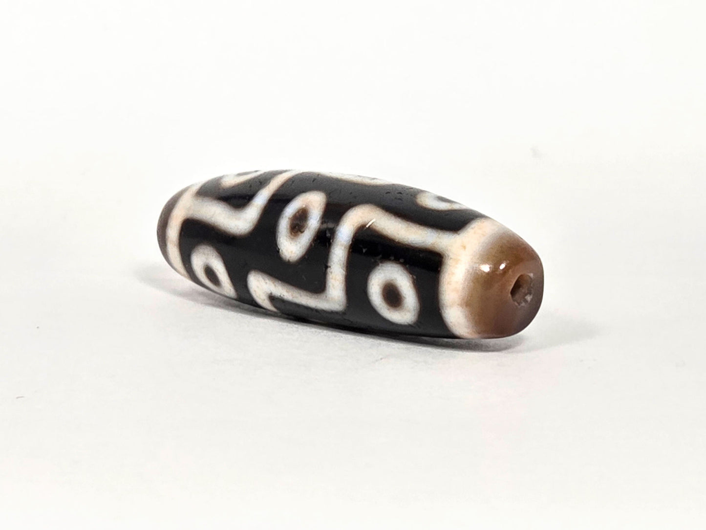 At-070626-9EBS nine eye dzi, angled drill end A, warm brown domed cap, small centred hole, black body, unretouched