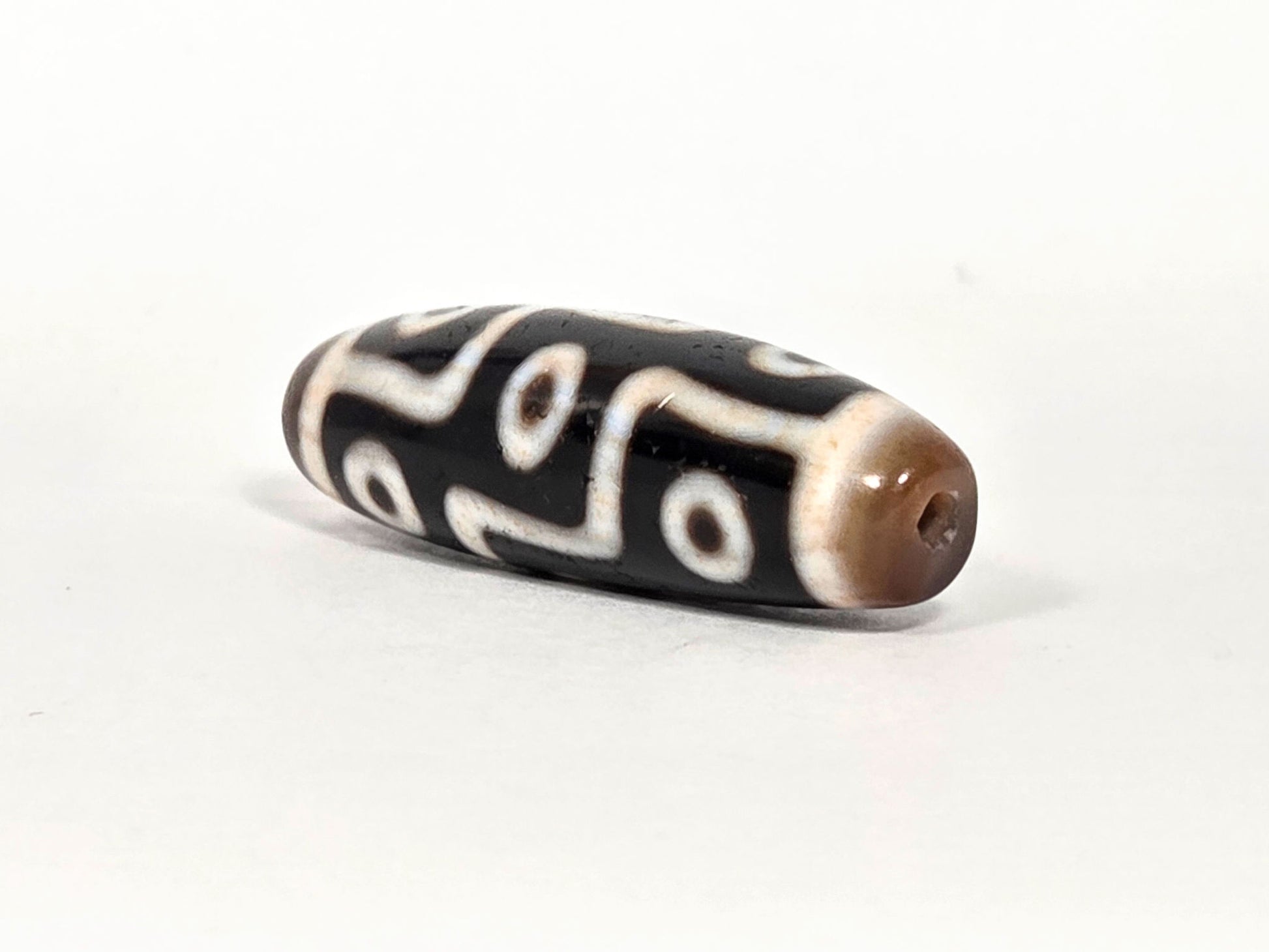 At-070626-9EBS nine eye dzi, angled drill end A, warm brown domed cap, small centred hole, black body, unretouched