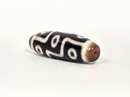 At-070626-9EBS nine eye dzi, angled drill end A, warm brown domed cap, small centred hole, black body, unretouched