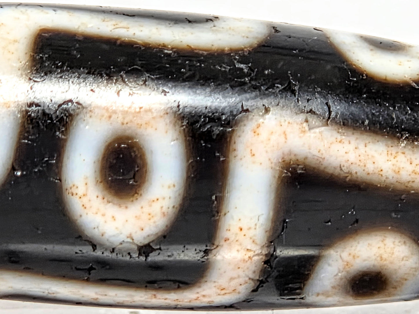 At-070626-9EBS macro, cinnabar bloodspot micro-dots in cream connector band zones, warm-toned motif lines, unretouched